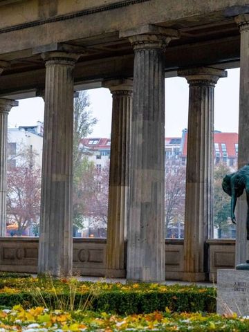 Historische Säulengalerie mit Park und Statue im Hintergrund
