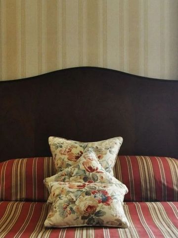 Bett mit gemusterten Kissen und gestreiftem Kopfteil im Hotelzimmer