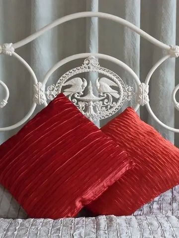 Detail eines kunstvoll verzierten Bettes mit roten Kissen und dekorativen Elementen