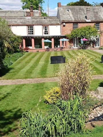 Gepflegter Garten vor einem historischen Gebäude mit Sitzgelegenheiten