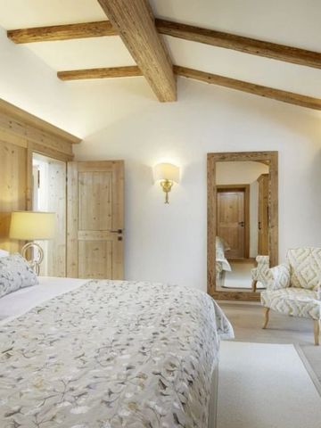Elegantes Schlafzimmer mit Holzbalken und großer Spiegel im Tennerhof Chalet