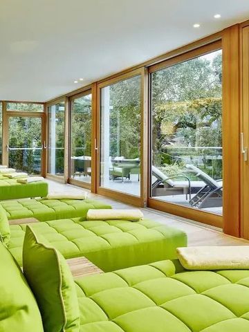 Heller Ruheraum mit grünen Liegen und Blick in den Garten