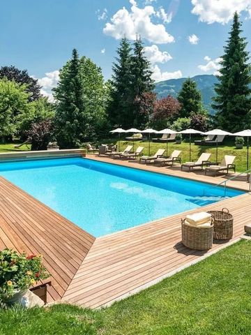 Außenpool mit Liegestühlen im Garten umgeben von Bergen