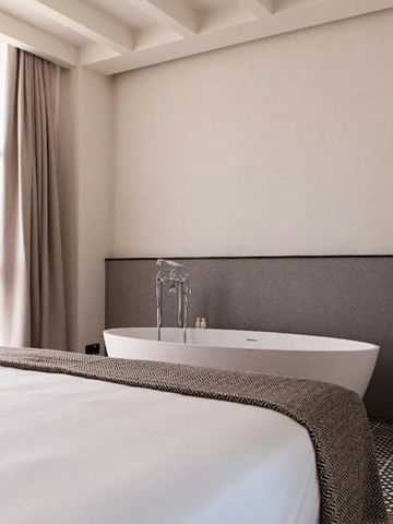 Geräumiges Schlafzimmer mit freistehender Badewanne und Fenster.