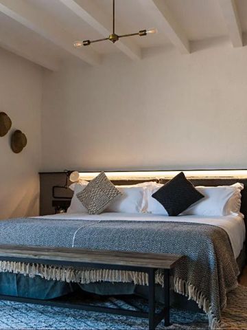 Komfortables Schlafzimmer mit gepolstertem Kopfteil und moderner Beleuchtung.