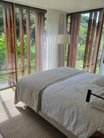 Lichtdurchflutetes Schlafzimmer mit großen Fenstern und Blick auf Weinberge.