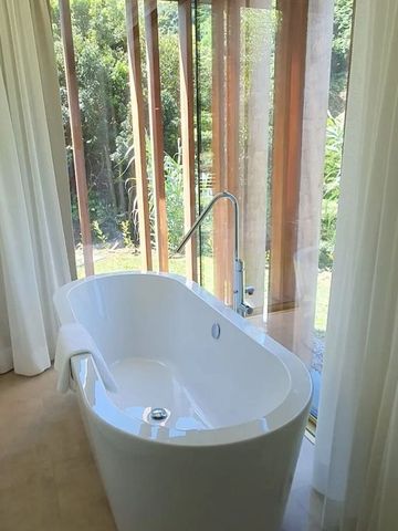 Freistehende Badewanne mit großen Fenstern und Blick ins Grüne.