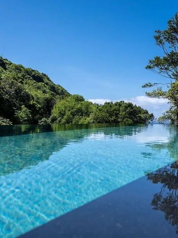 Klares Wasser im Infinity-Pool mit Wald und Himmel im Hintergrund