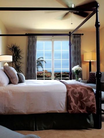 Geräumiges Schlafzimmer mit Himmelbett und großem Fenster mit Meerblick