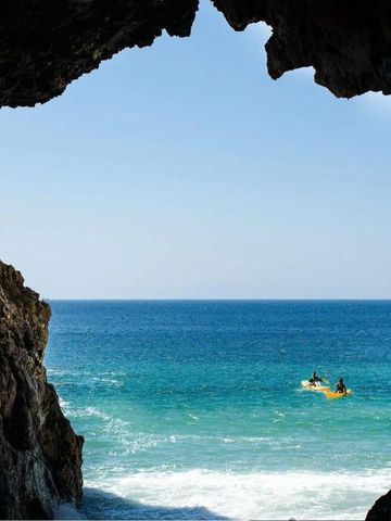 Blick auf das Meer durch eine Felsenöffnung mit Booten im Wasser