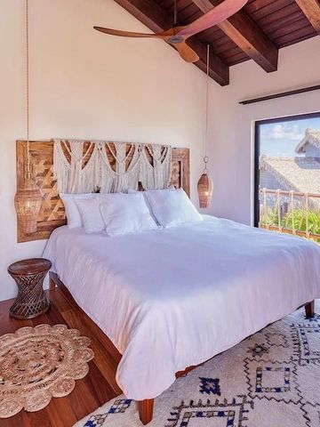 Schlafzimmer mit Deckendecke und Blick auf eine Terrasse mit tropischem Ambiente