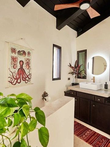 Stilvolles Badezimmer mit Kunst an der Wand und üppigem Pflanzenakzent