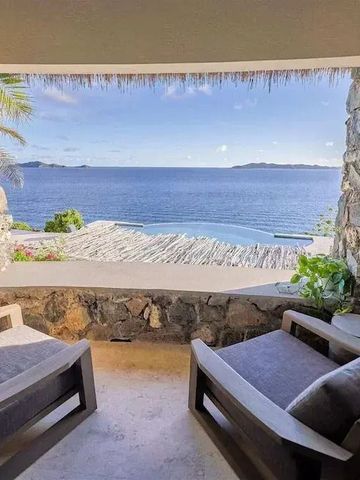 Blick von einer Terrasse auf das Meer mit zwei Sesseln im Vordergrund.