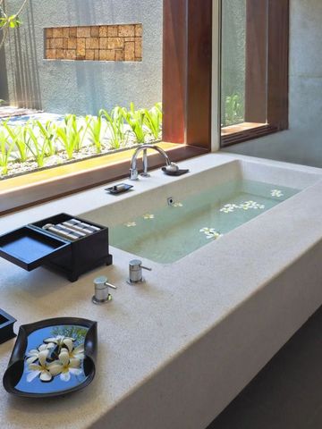 Luxuriöses Badezimmer mit großer Badewanne und Ausblick auf Grünfläche.