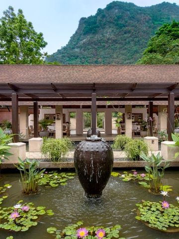 Japanischer Garten mit Seerosen und zentralem Wasserspiel vor Bergkulisse
