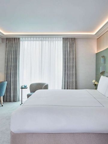 Modernes Zimmer in neutralen Tönen mit stilvoller Einrichtung und großem Fenster.