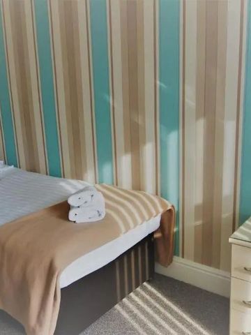 Einzelbett in Zimmer mit gestreifter Tapete und natürlichem Licht