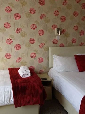 Hotelzimmer mit Doppelbett und roter Akzentdecke