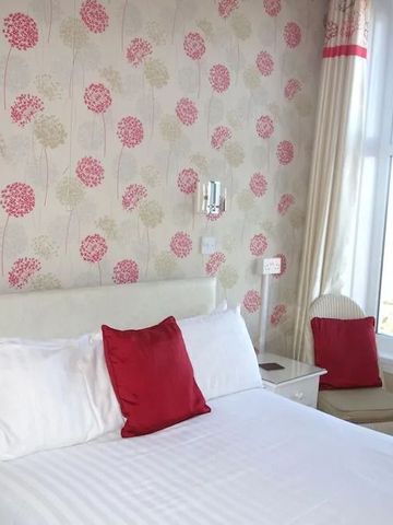 Gemütliches Hotelzimmer mit floralem Tapetendesign und Tageslicht.