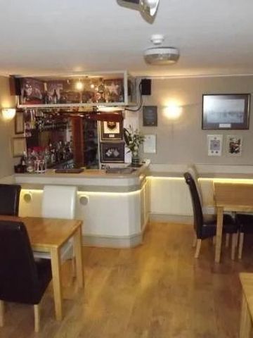 Gemütliche Hotelbar mit Holztischen und Stühlen in warmen Farben.