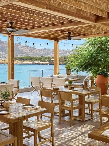 Restaurantterrasse mit Holzmöbeln und Blick aufs Meer
