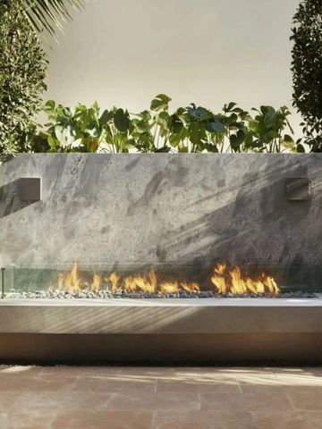 Moderner Außenkamin mit bequemen Sitzbänken im Garten des Hotels