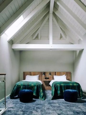 Dachzimmer mit Holzbalken und zwei Einzelbetten