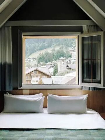 Zimmer in Dachschräge mit großer Fensterfront und Blick auf die Berge