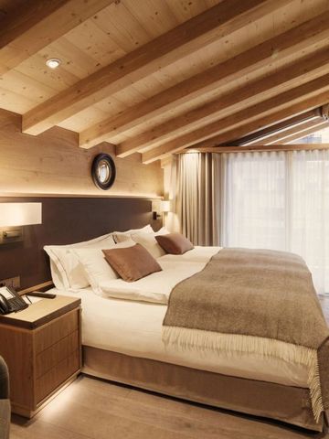 Gemütliches Hotelzimmer mit Holzbalkendecke und luxuriösem Doppelbett