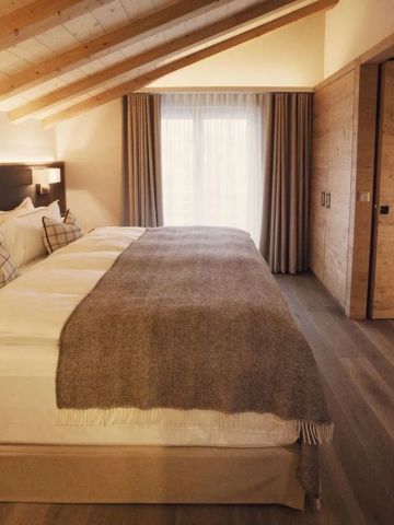 Elegantes Schlafzimmer mit Holzbalkendecke im alpinen Stil des Hotels The Capra Saas-Fee