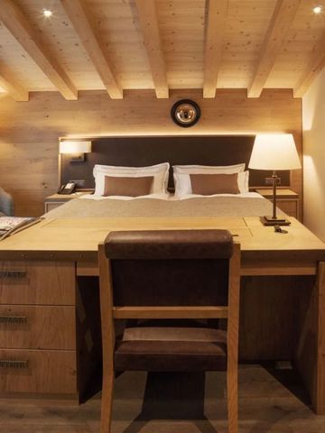 Einladendes Schlafzimmer mit Holzmöbeln und gemütlicher Beleuchtung im Hotel The Capra Saas-Fee