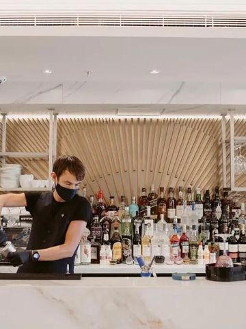 Moderne Hotelbar mit Barkeeper und vielfältiger Getränkauswahl im Hintergrund.