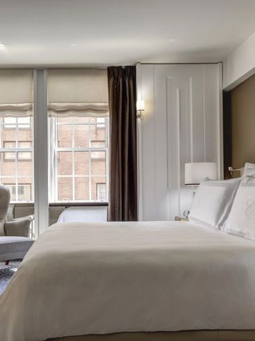 Wohnliches Hotelzimmer mit eleganter Möblierung und klassischem Stil. Große Fenster