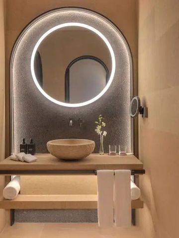 Elegantes Badezimmer mit rundem Spiegel und Steinwaschbecken