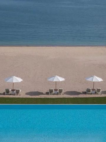 Infinity-Pool mit Blick auf Sandstrand und Meer unter Sonnenschirmen