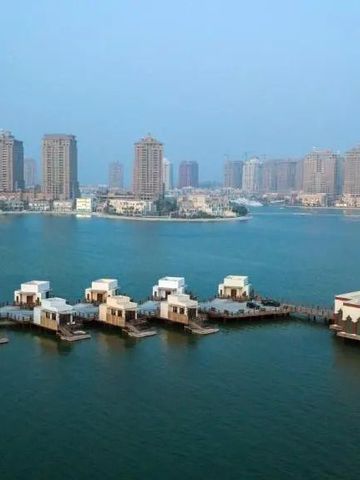 Überblick über Wasserbungalows mit städtischem Hintergrund bei ruhiger See