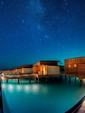 Überwasserbungalows bei Nacht mit Sternenhimmel