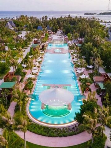Panoramablick auf großen Infinity Pool unter Palmen in malerischer Umgebung