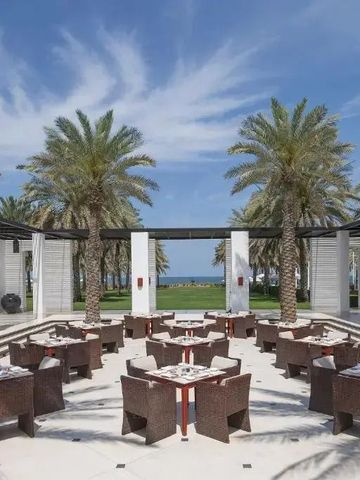 Terrassenrestaurant mit Rattanmöbeln und Palmen im Freien.