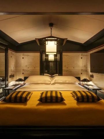 Gemütliches Zimmer mit großem Bett und eleganter Beleuchtung in warmen Farbtönen.