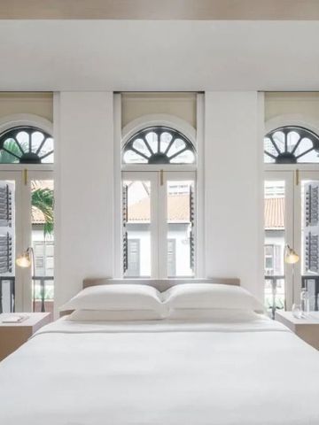 Elegantes Schlafzimmer mit weißen Möbeln und historisch gestalteten Fenstern