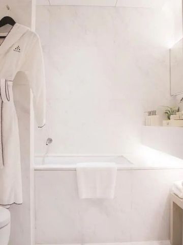 Helles Badezimmer mit einem weißen Bademantel und einer Badewanne