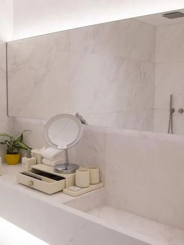 Modernes Badezimmer mit eleganten Toilettenartikeln und weitem Spiegel