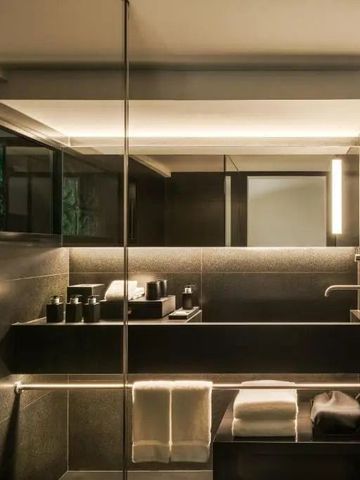 Modernes Badezimmer mit dunklen Fliesen und eleganter Beleuchtung