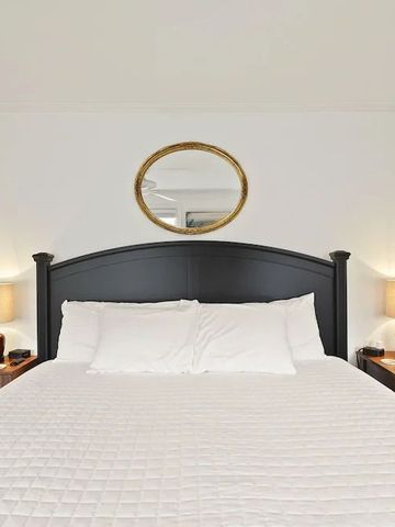 Großes Bett mit symmetrischer Anordnung der Nachttische und Spiegel