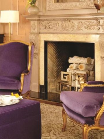Elegantes Wohnzimmer mit lila Sesseln und Kamin.