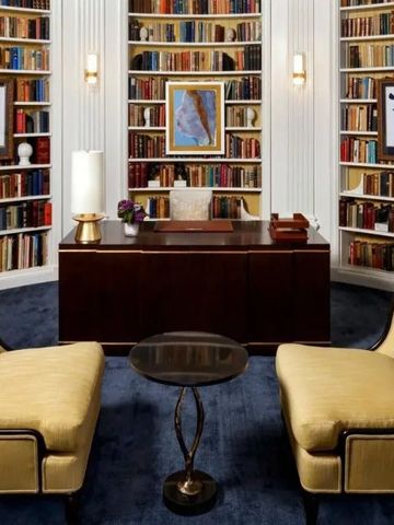 Bibliothek mit reich verzierten Bücherregalen und luxuriösem Sitzbereich.