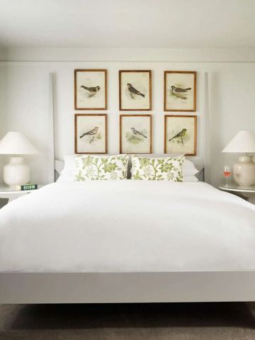Helles Schlafzimmer mit Himmelbett und Vogelbildern an der Wand