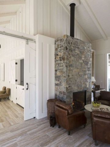 Wohnbereich mit Steinmauer, bequemen Ledersesseln und viel natürlichem Licht