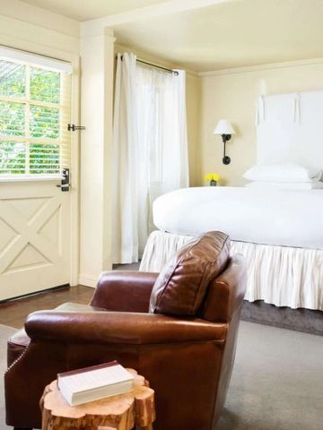 Helles Zimmer mit großen Fenstern und einem gemütlichen Lederstuhl